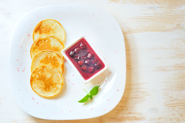 Pancakes with cherry jam in square  plate on the wooden table
