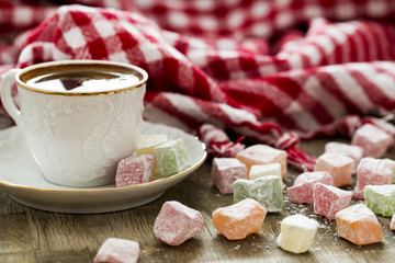 Fototapeta na wymiar Turkish coffee, red plaid cloth and colored sweets on the wooden table 