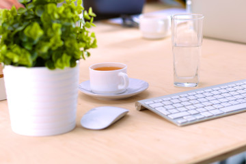 Close up view of a work desk interior with a laptop computer, a cup of coffee and white curtains on a sunny day