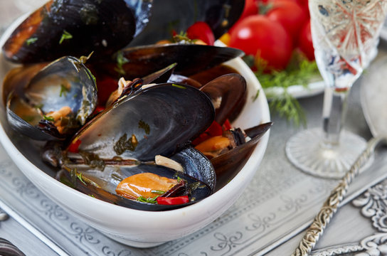 Delicious mussels with sauce and a glass of white wine on a tray