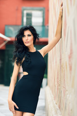 Naklejka premium Brunette woman wearing black seductive dress in the street