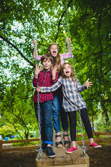 Fototapeta premium Smiling kids having fun at playground. Children playing outdoors in summer. Teenagers riding on a swing outside