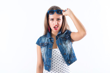 Studio portrait of a playful girl having fun, wearing sunglasses and trendy summer outfit.