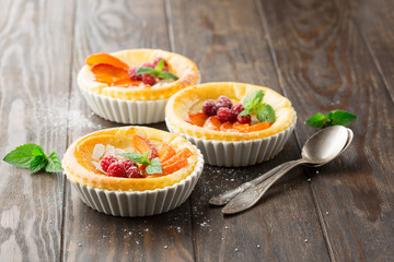 Tartlets with cottage cheese and fresh fruits on rustic wooden background, selective focus