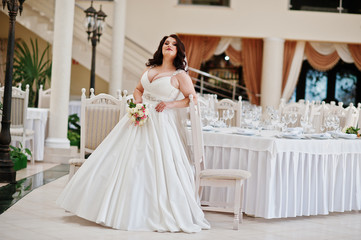 Big breasts brunette bride with wedding bouquet posed at wedding