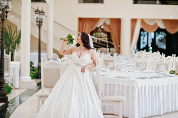Big breasts brunette bride with wedding bouquet posed at wedding