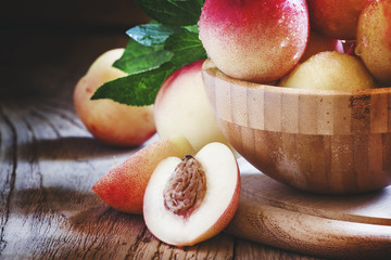 Fresh white nectarines in a wooden bowl, selective focus