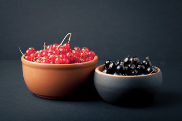 Currant berries in a clay bowl on black background. Selective fo
