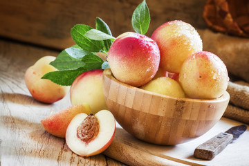 Fresh white nectarines in a wooden bowl, selective focus