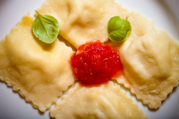 Russian ravioli - pelmeni with tomato sauce and basil on a white