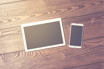 White digital tablet and smart phone on wooden table