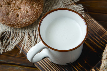 cup of warm milk and bread on a wooden background