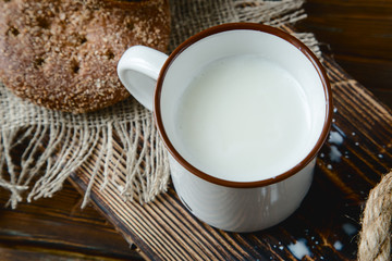 cup of warm milk and bread on a wooden background