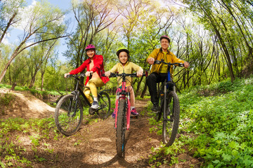Happy family mountain biking on forest trail