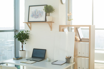 Side view picture of studio workplace with blank notebook, laptop. Designer comfortable work table, home office.
