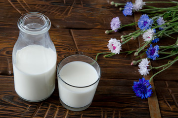 Bottle with milk and glass of milk at wooden table.