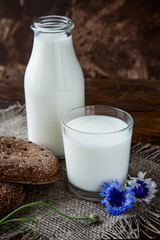 Bottle with milk and glass of milk at wooden table.