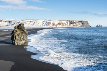 Obraz premium Big basalt rock on the Reynisfjara black sand beach, view from Dyrholaey. Vik, South Iceland.