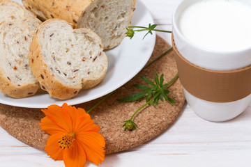 A cup of fresh milk and sliced homemade bread with the flax seeds and sun dried tomatoes