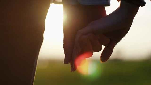 4K Hands of a young couple come together at sunset, in slow motion