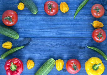 vegetables on blue wooden table. red and yellow peppers, cucumber, tomato, chilli and habanero peppers. Image with copy space.