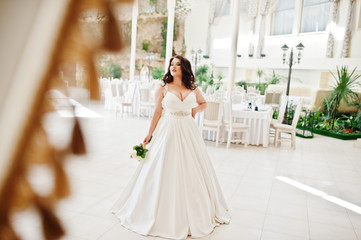 Big breasts brunette bride with wedding bouquet posed at wedding
