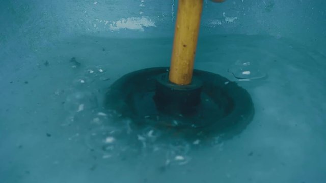 Black rubber plunger cleans the bathroom drainage. In the water is large bubbles and a lot of dirt. Slow motion, high speed camera, 250fps