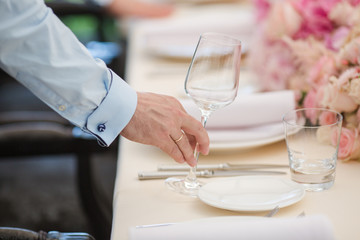 Waiters is serving dinner place on a wedding in a restaurant. Table decorated with flowers