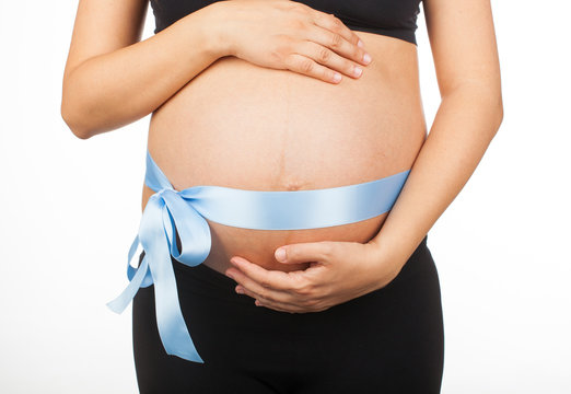 Pregnant woman with pink ribbon around her belly.