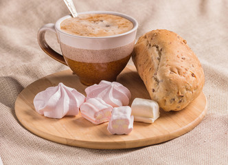 sweet buns, meringues and coffee cup on a wooden board