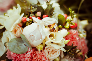Beautiful engagement rings lie on the original wedding bouquet of flowers