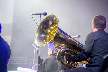 Tubaist in an orchestra on the stage, holds big brass tube, behind the scenes shoot