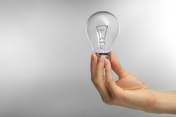 Woman hand holding bulb on grey background