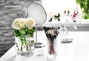 Cosmetic brushes with bouquet on light dressing table