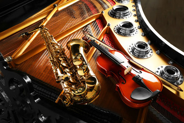 Naklejka premium Violin and saxophone lying on piano, close up