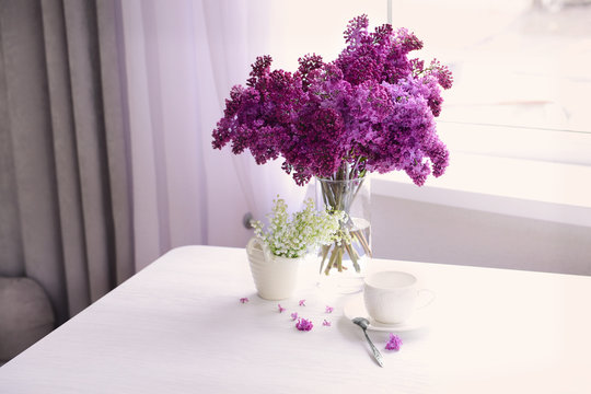 Lilac and may-lily bouquets on white table