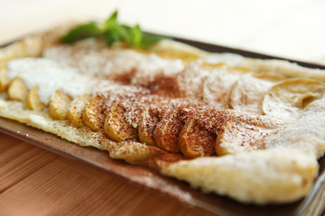 Baked apple dessert in black plate on wooden background