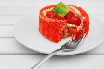 Strawberry biscuit cake with fork in white plate on light wooden table