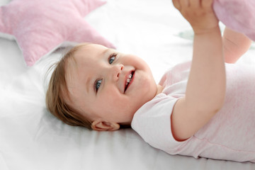 Obraz na płótnie Canvas Adorable smiling baby girl on a white sheet