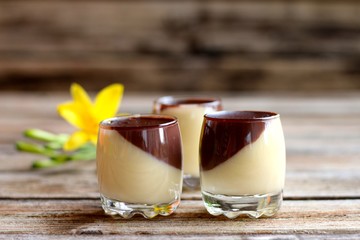 zweifarbiger pudding mit lilie auf alten holzbrett © Gerda Lehner