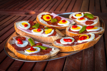 Traditional hungarian sandwiches with salami, ham, boiled egg and sweet pepper cream on the top