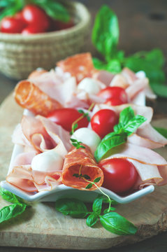 Ham, salami, antipasto, mozzarella and bocconcini soft cheese, selective focus, toned image