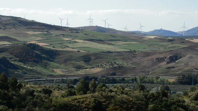 Landscape of fields with wind turbines tower energy rotating with highway with traffic