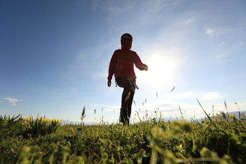 Fototapeta premium silhouette of young woman backpacker hiking on sunrise mountain peak