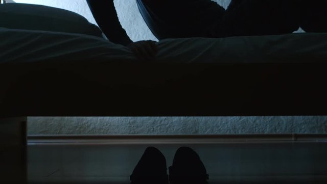 SILHOUETTE: Man gets up from a bed in the night then wears a slippers and goes