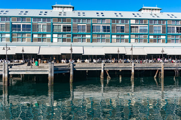 Fototapeta na wymiar Finger wharf restaurant in Woolloomooloo bay with unrecognisable people in the distance. Sydney, Australia