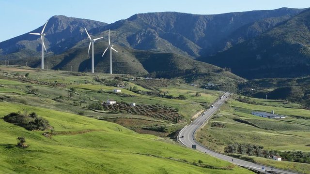 Landscape of mountains and green fields with wind turbines energy renewable towers moving at sunny day