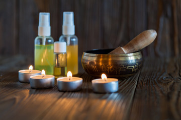 singing bowl on dark wooden background. Burning candles and oil for aromatherapy and massage..