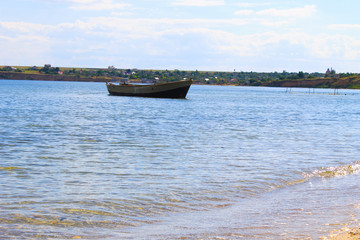 Old fishing boat at anchor in sea near sand shore