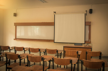 University classroom with desks, blackboard and screen projecter